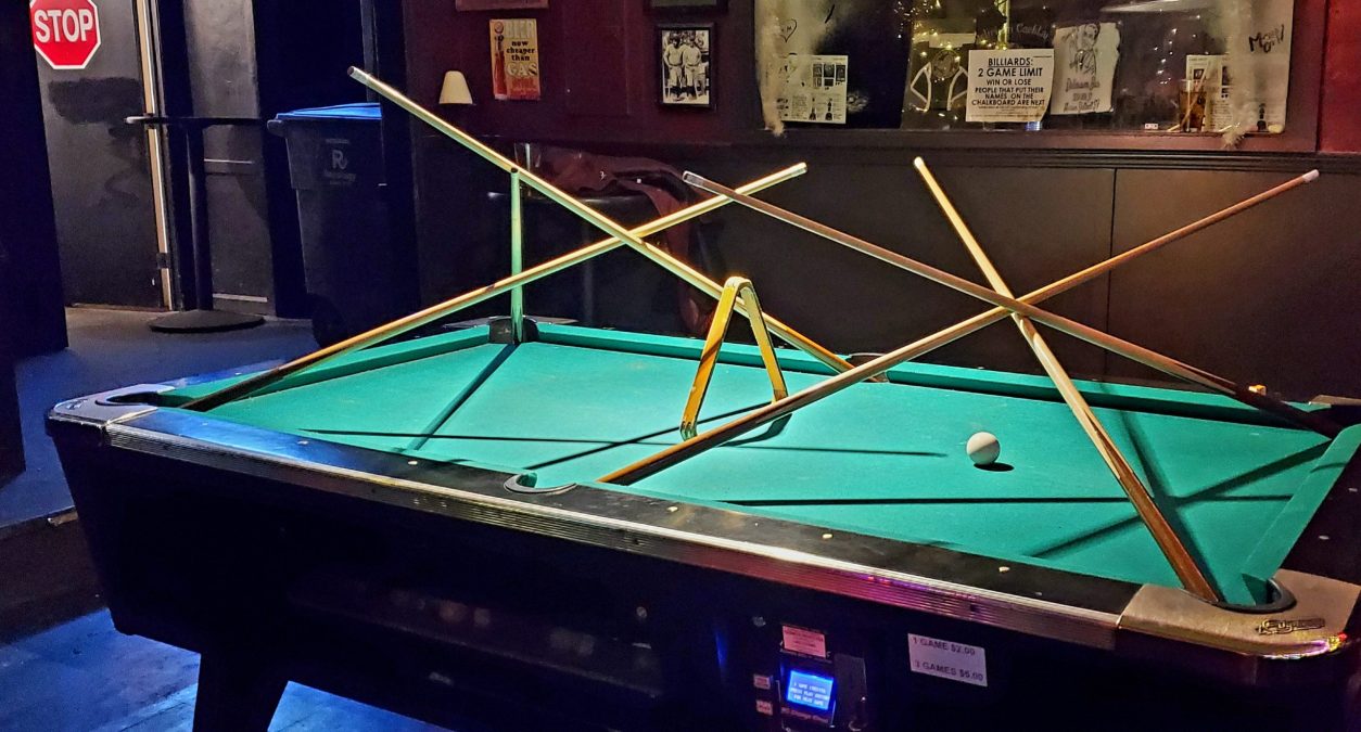 A green felt topped pool table with a stick structure on top of it.