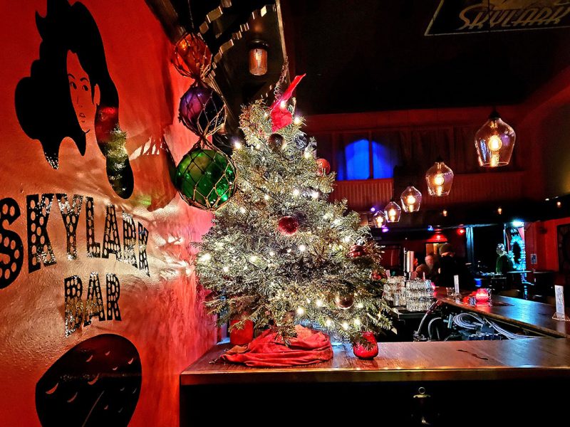 A Christmas tree on top of a bar, with lights across it.