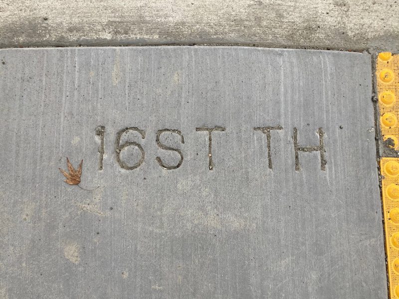A sidewalk with a misspelled street name cut into the cement.