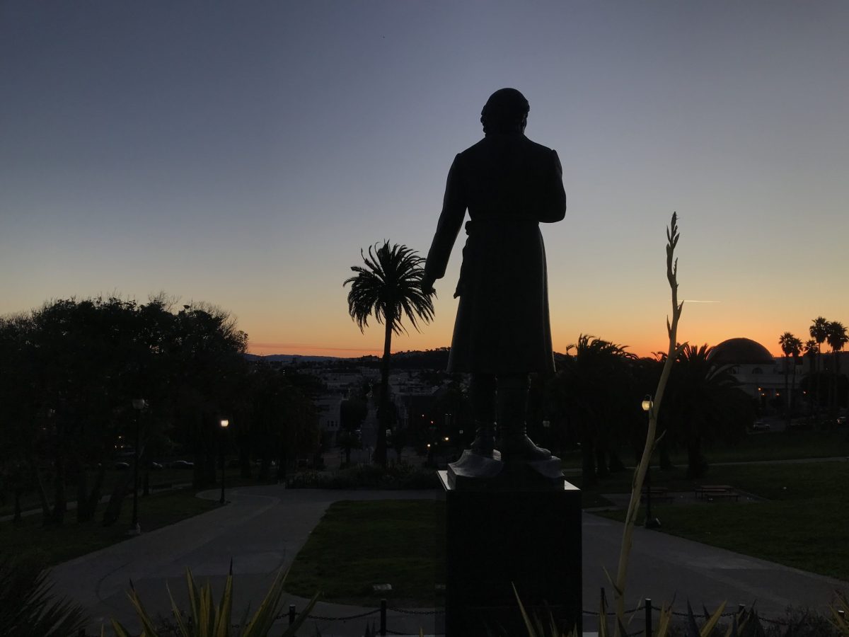 A statue of Hidalgo, his back to us, looking at the sunrise.