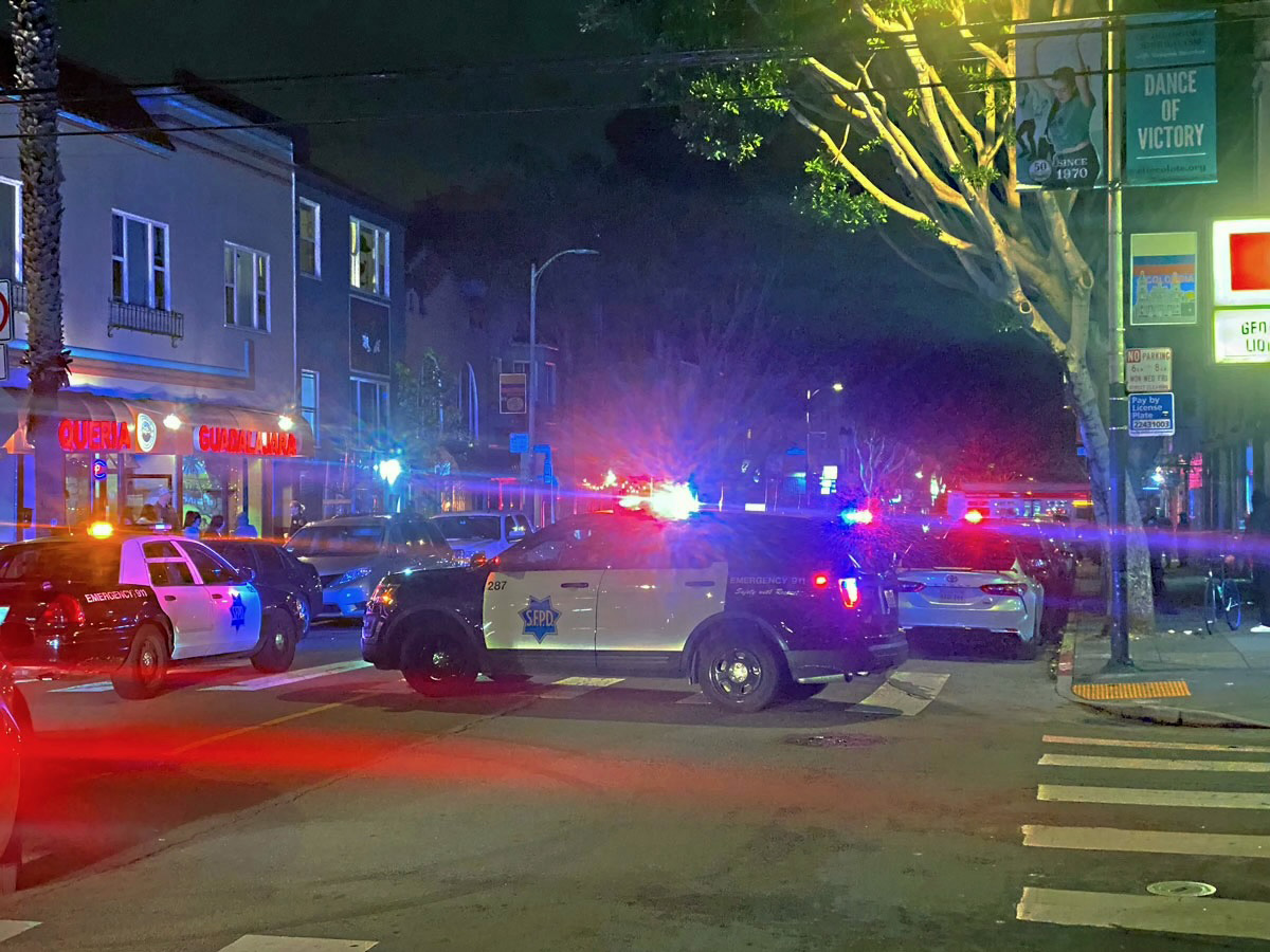 Yellow caution tape in front. Police cars blocking the intersection.