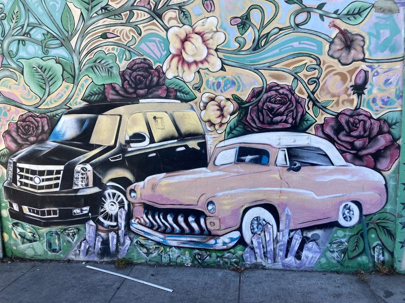 Two old cars in a painted mural.