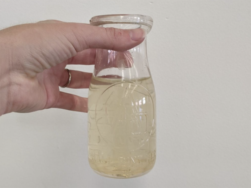 Someone holding up a bottle of contaminated water