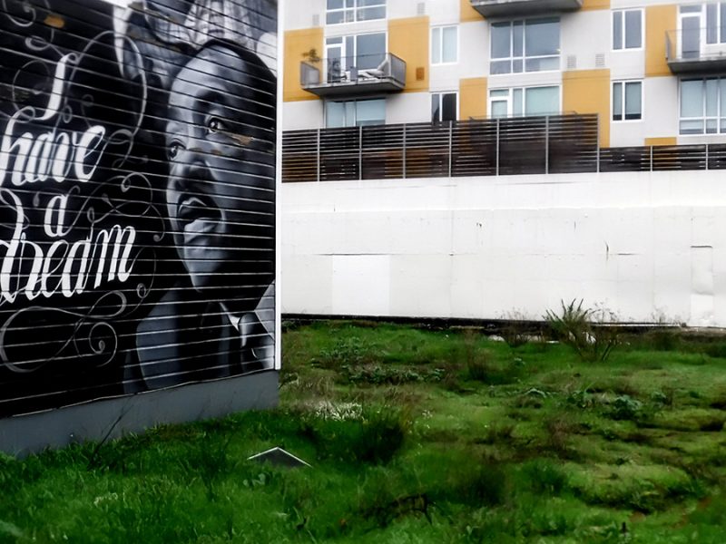 A mural with Martin Luther King, Jr. and I have a Dream that looks over an empty lot with apartment balconies to the north.