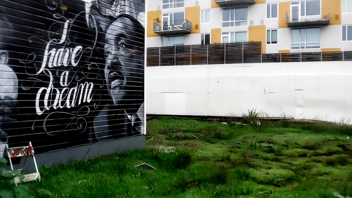 A mural with Martin Luther King, Jr. and I have a Dream that looks over an empty lot with apartment balconies to the north.