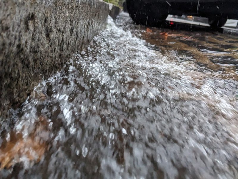 A tilted view of a curb, with water rushing down it.