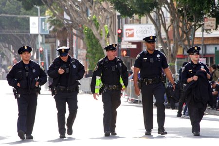 Five police officers marching down the road.