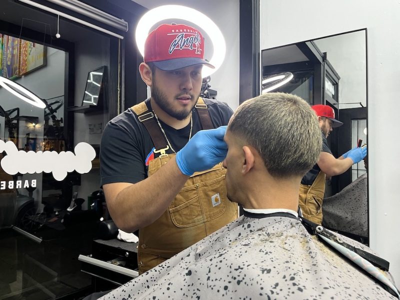 Barber trimming hair at barbershop