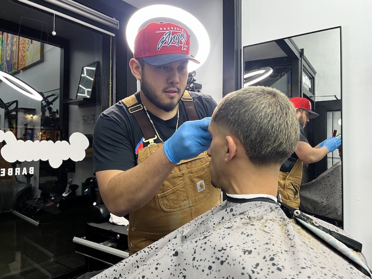 Barber trimming hair at barbershop