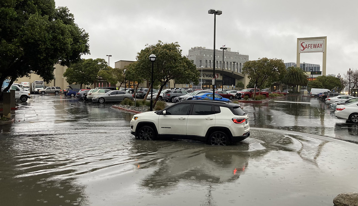 A car in lots of water at the Safeway parking lot.