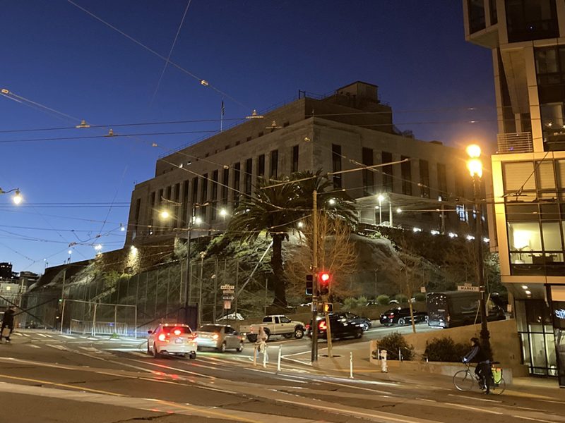 A big building up on a slight hill on a city street.