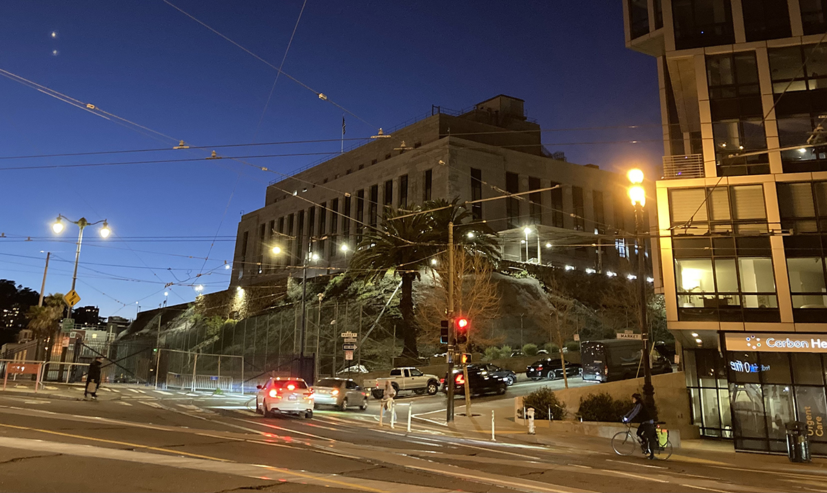 A big building up on a slight hill on a city street.