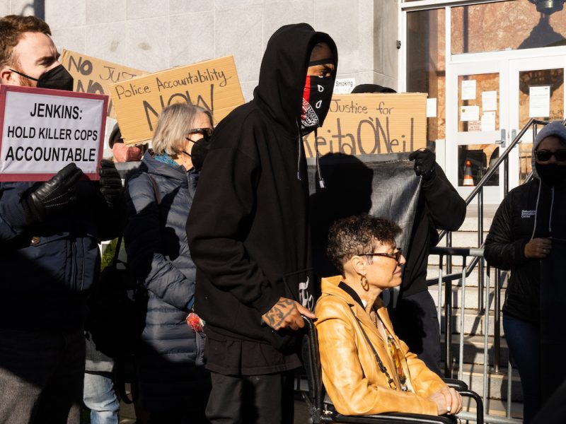 man pushing woman in wheelchair protest