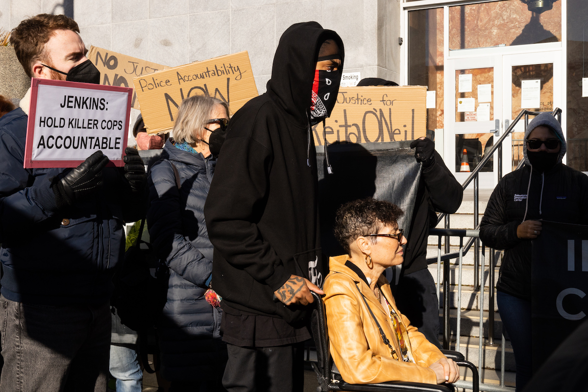 man pushing woman in wheelchair protest