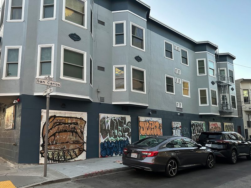 A line of garage doors replaced by other boards with murals on them.