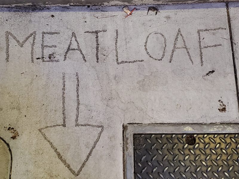 A large arrow pointing down in the cement with the word Meatloaf above it.