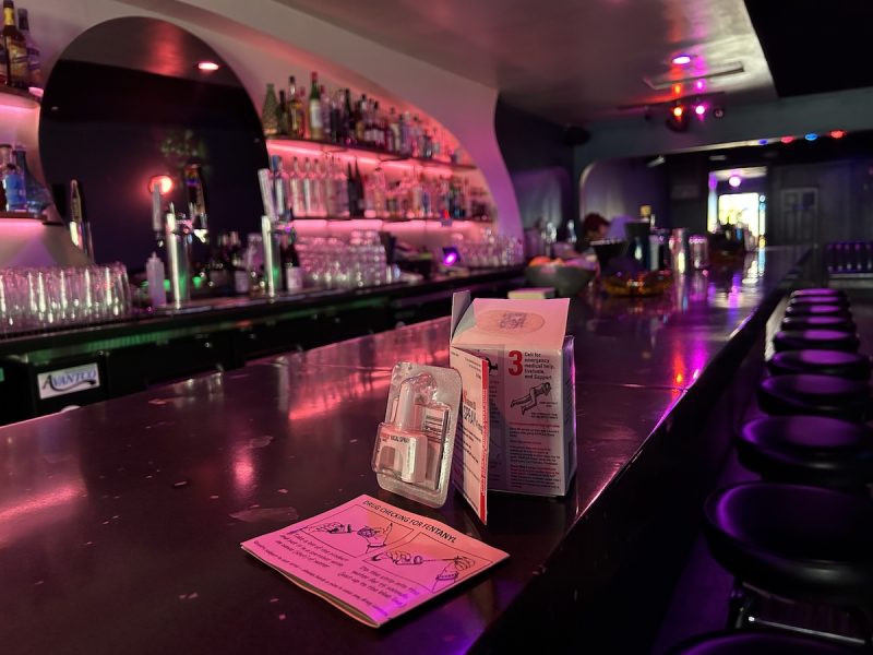 Mothership bar bathed in pink light, and naloxone and fentanyl test strips on the counter.