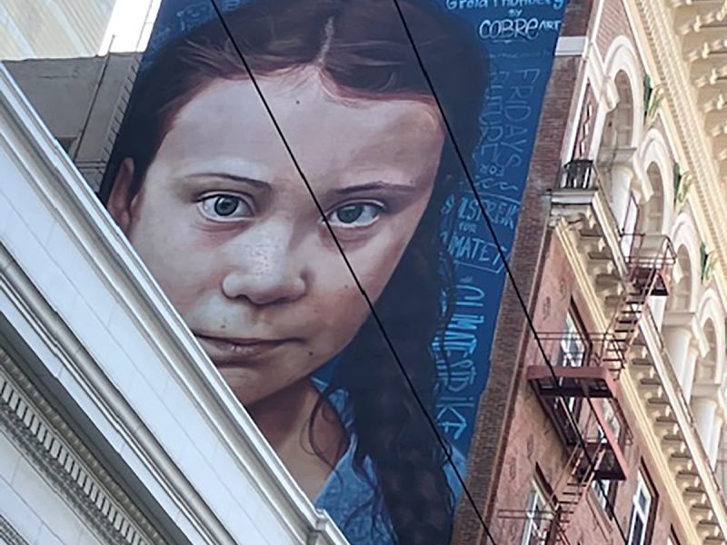 The side of a building with Greta Thunberg's face painted on it.