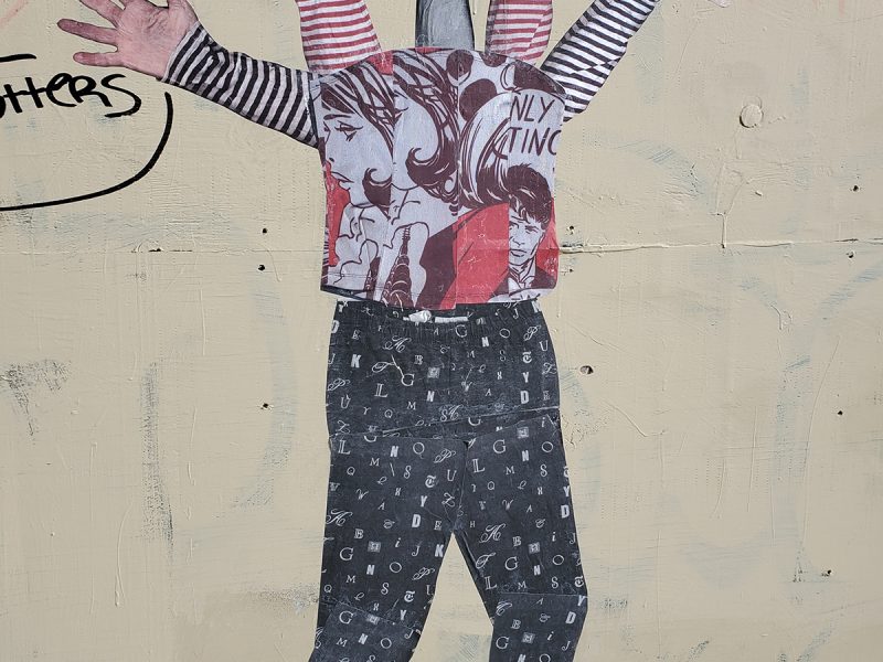 A figure painted on the wall with hands and arms instead of a head.