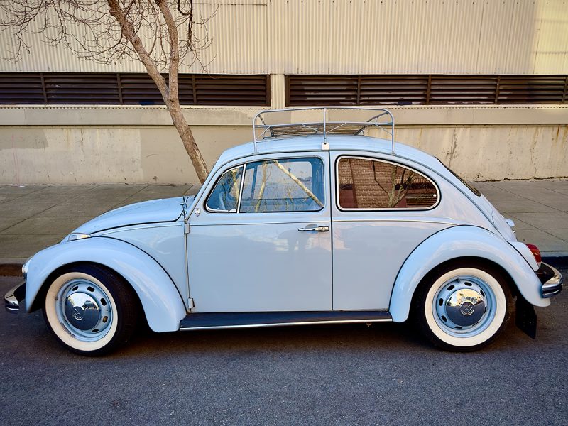 A light blue Volkswagen bug parked.