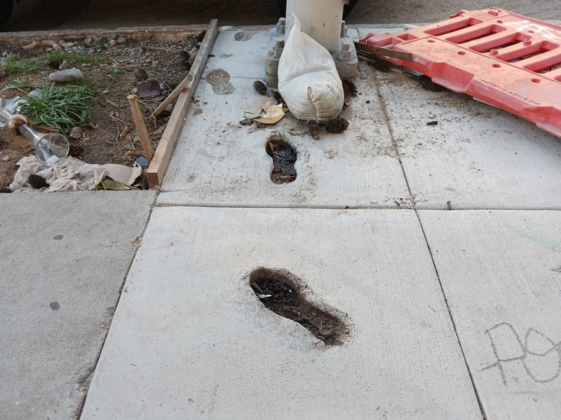 Cement with footsteps cut into it, a sandbag and a bong in a pile of dirt.