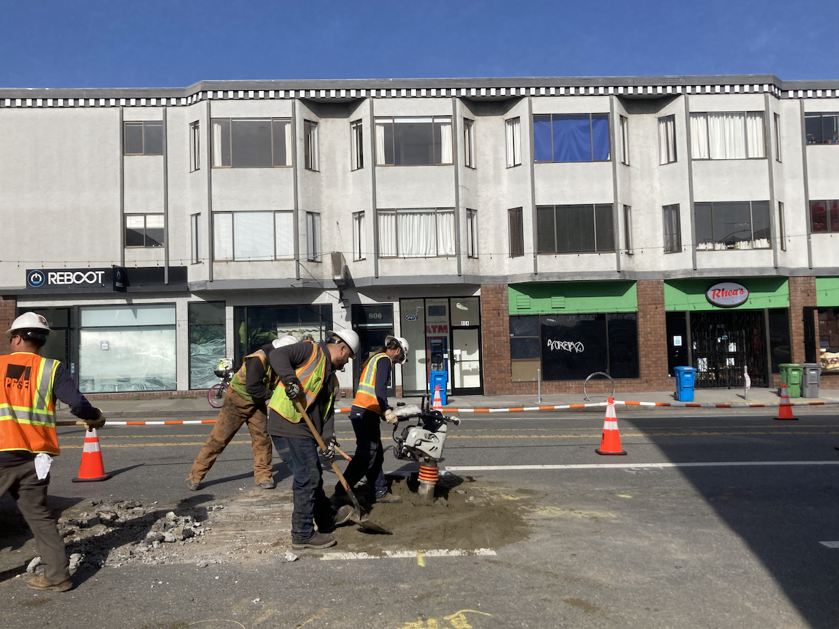 Workers dig and drill in the asphalt