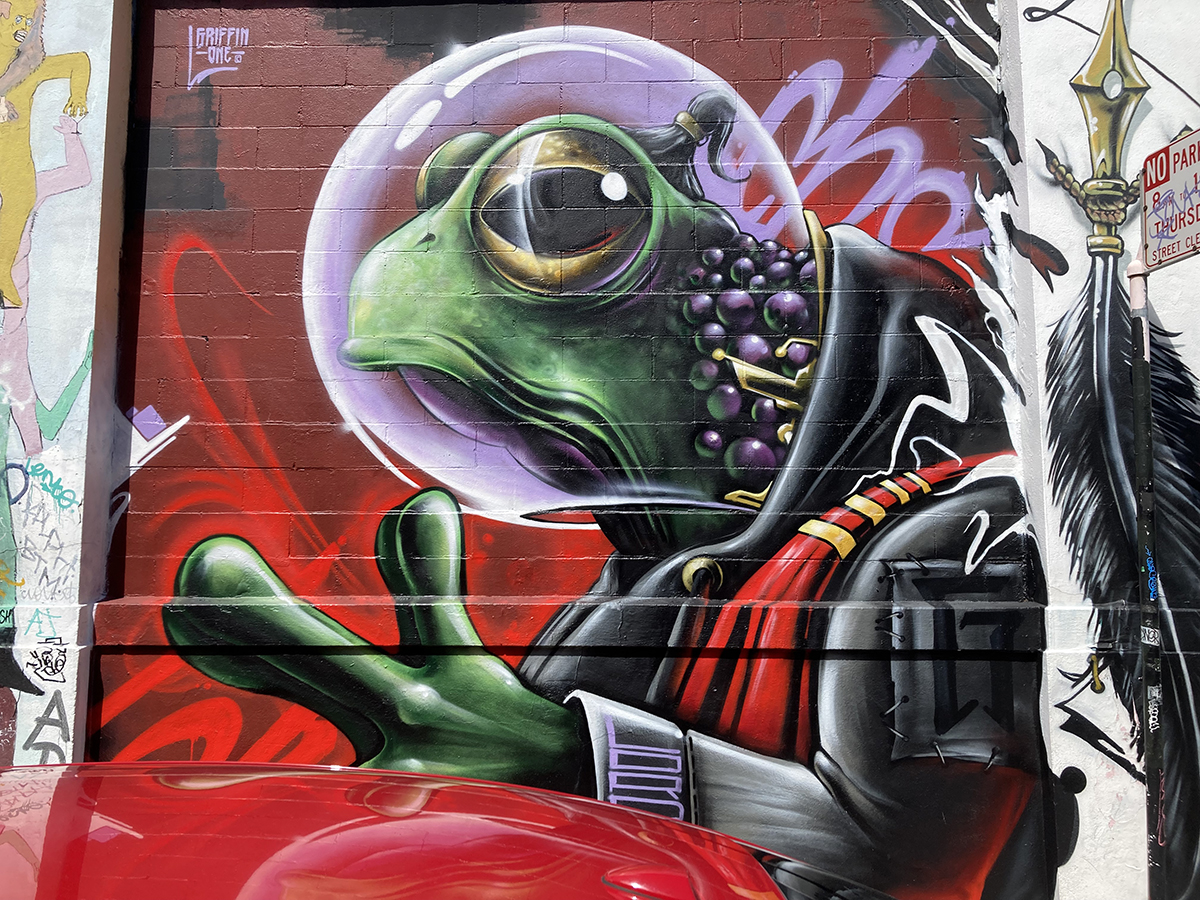 A frog with a bubble around its head, painted on a wall.