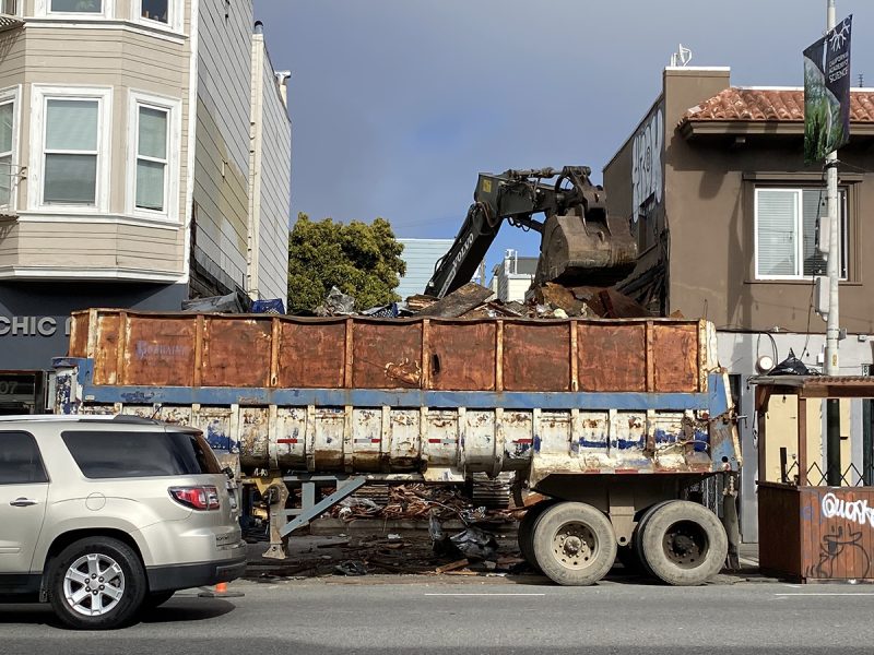 A large truck with a crane tossing material from the Phoenix Bar demolition into it.