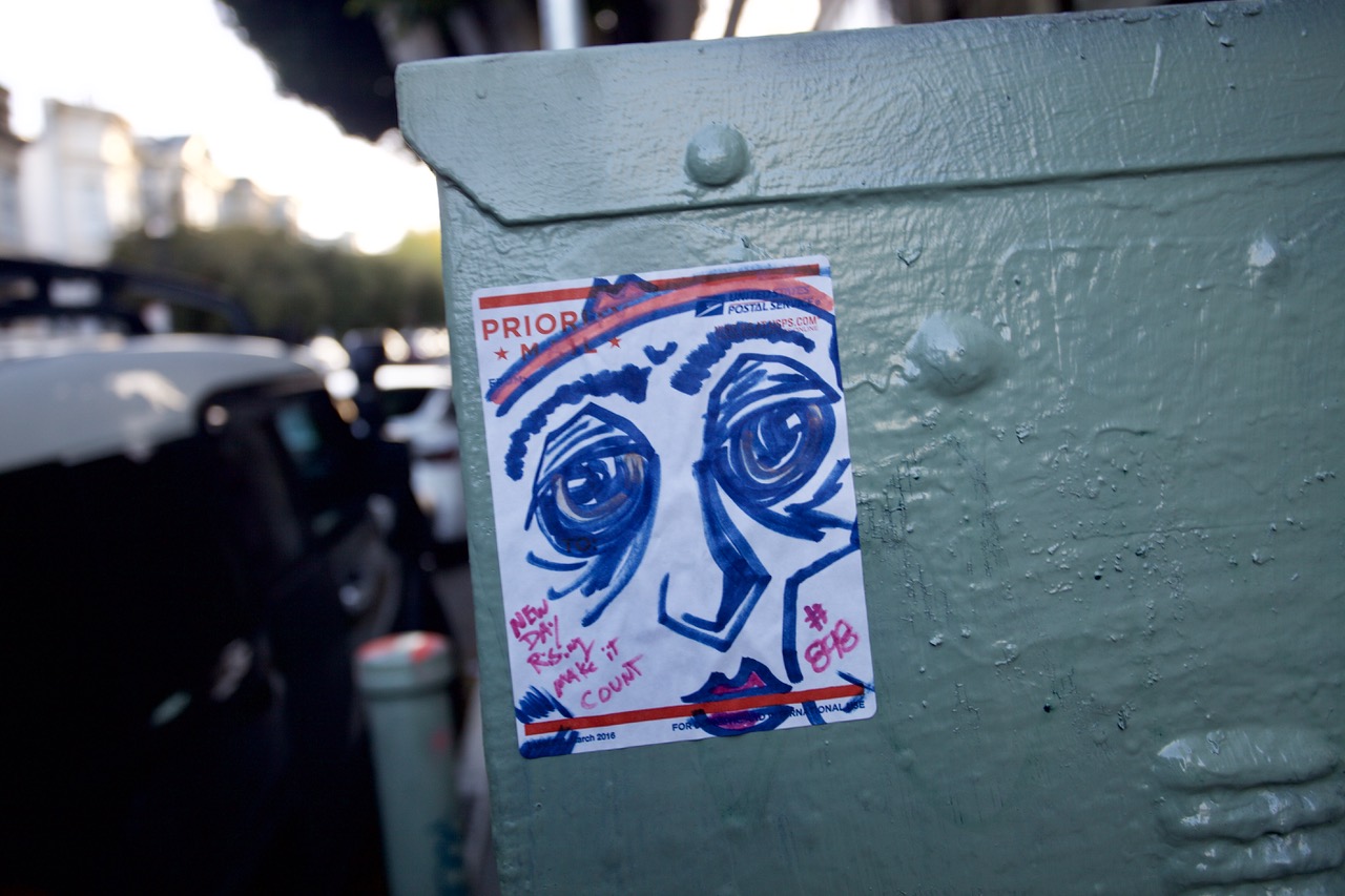 A flyer on a box, with a face in blue and pink marker.