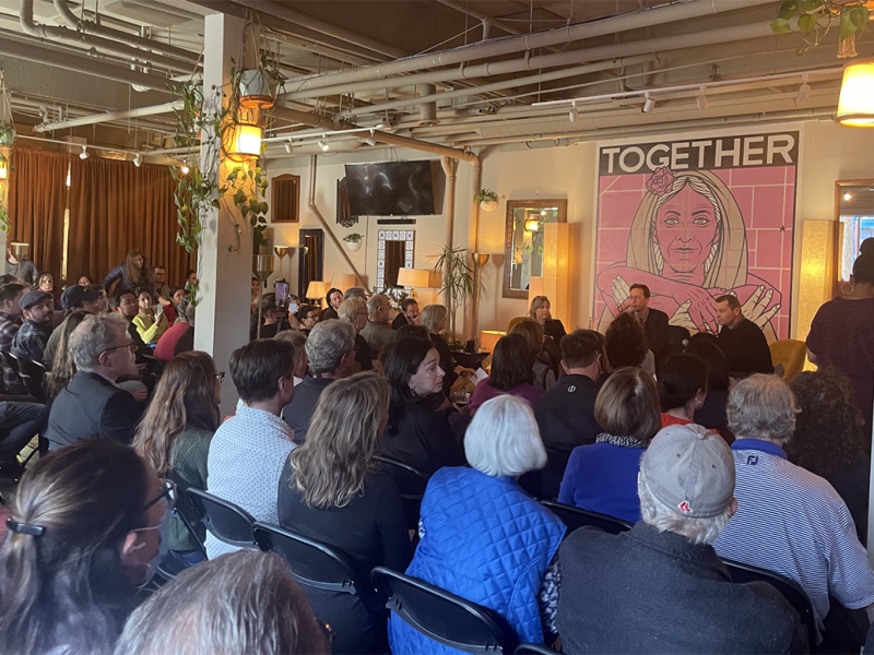 Three people sitting on a stage in front of a crowd.