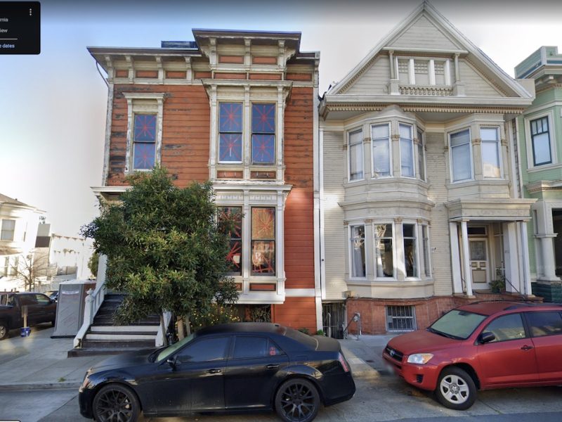 An orange Edwardian and a white Victorian prominently viewed on the street.