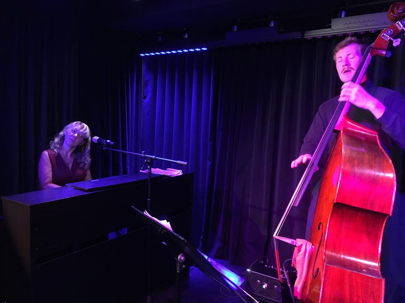 Gaea Schell playing the piano and a man with a cello.