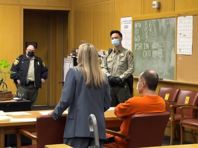 A woman stands next to a man in orange sweats
