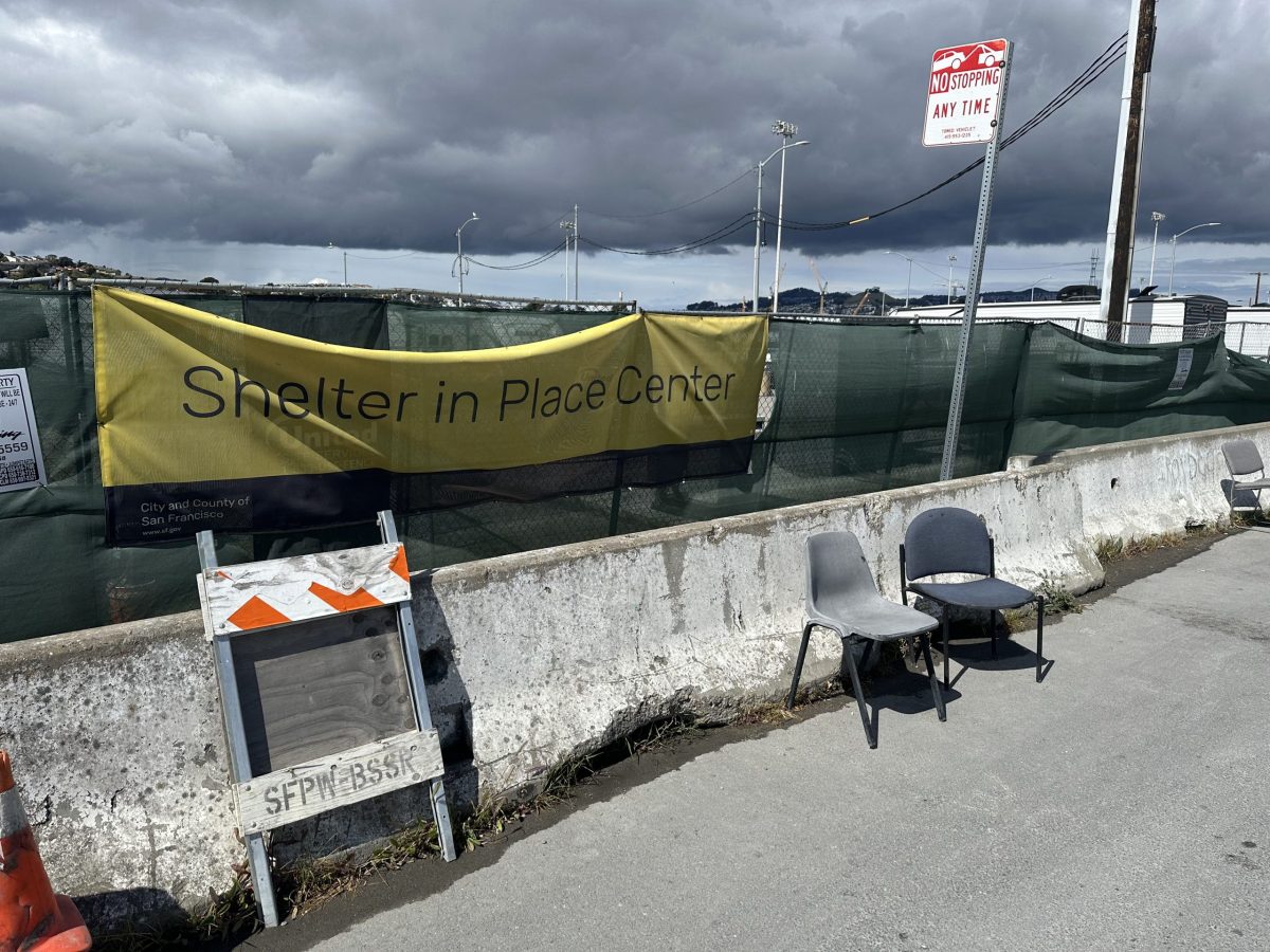 Two chairs in front of concrete bollards and a chain link fence