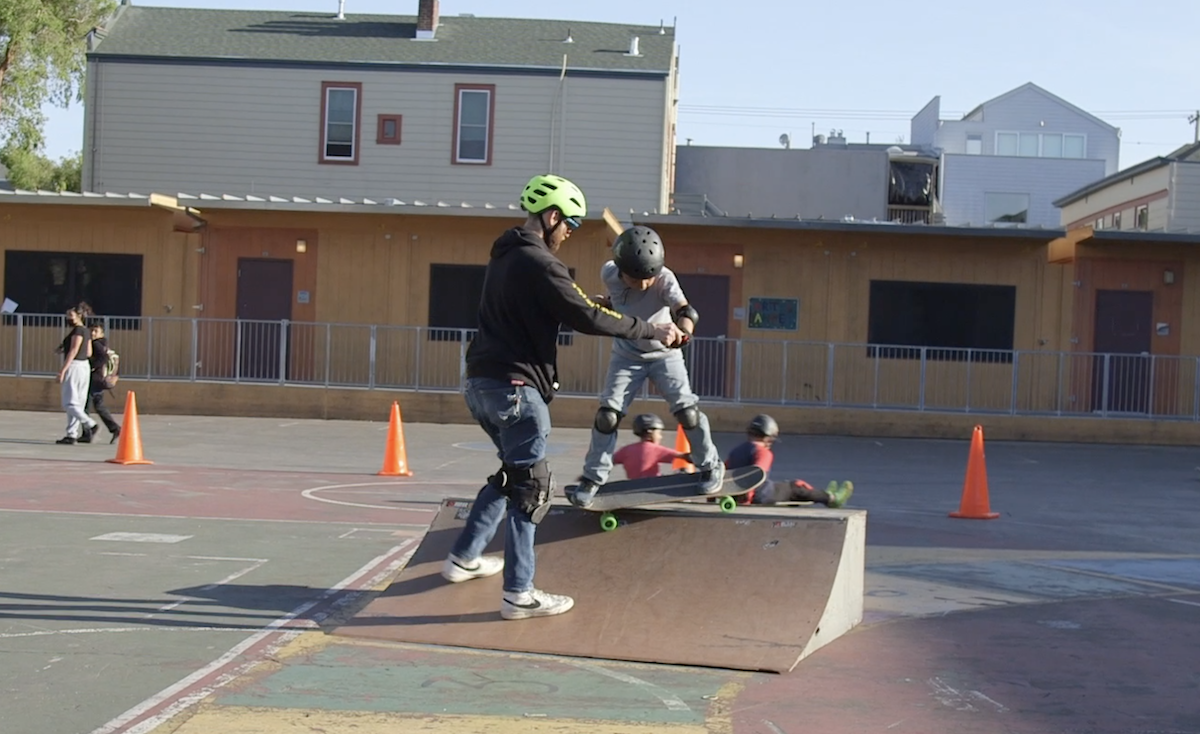 a man teaching a boy to skateboard on a ramp