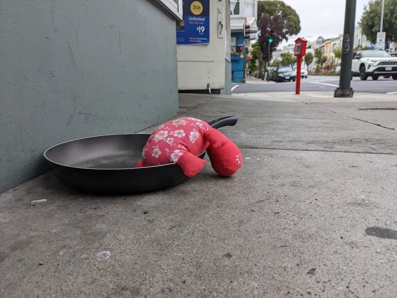 A discarded frying pan on a sidewalk.