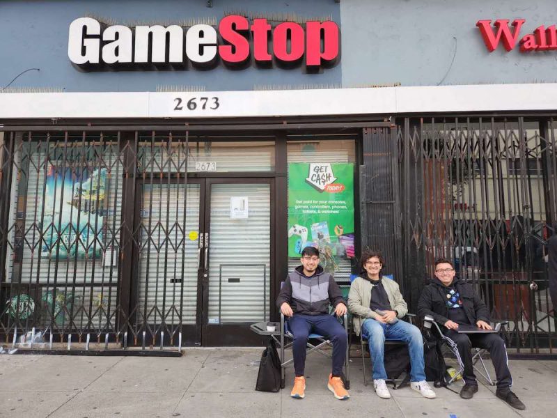 three men sitting in front of a store