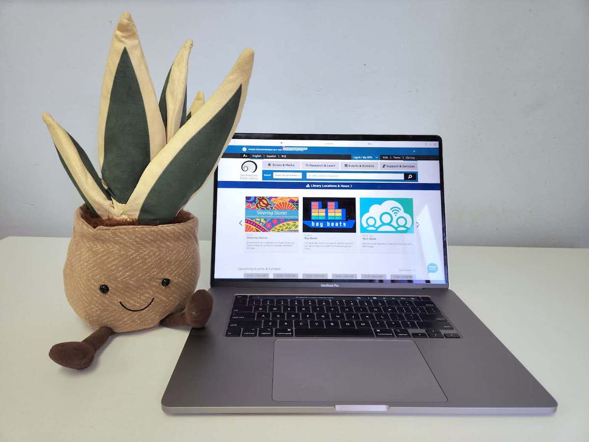 A plant plush next to a laptop.