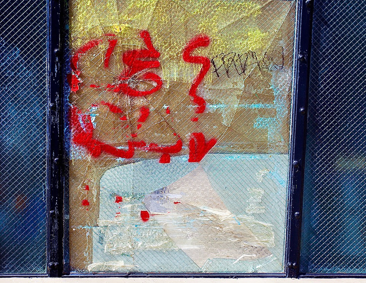A window covered with red and yellow paint and the word, fiasco.