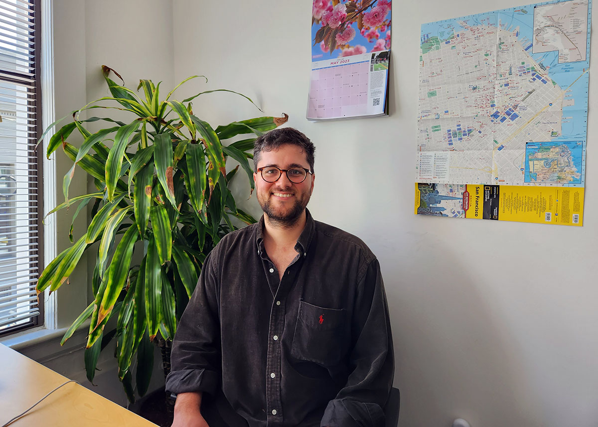 A. man sitting at a desk with a plant behind him.
