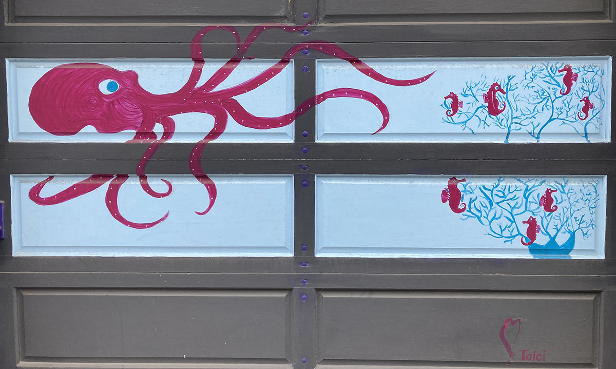 A purple octopus painted on a garage door.