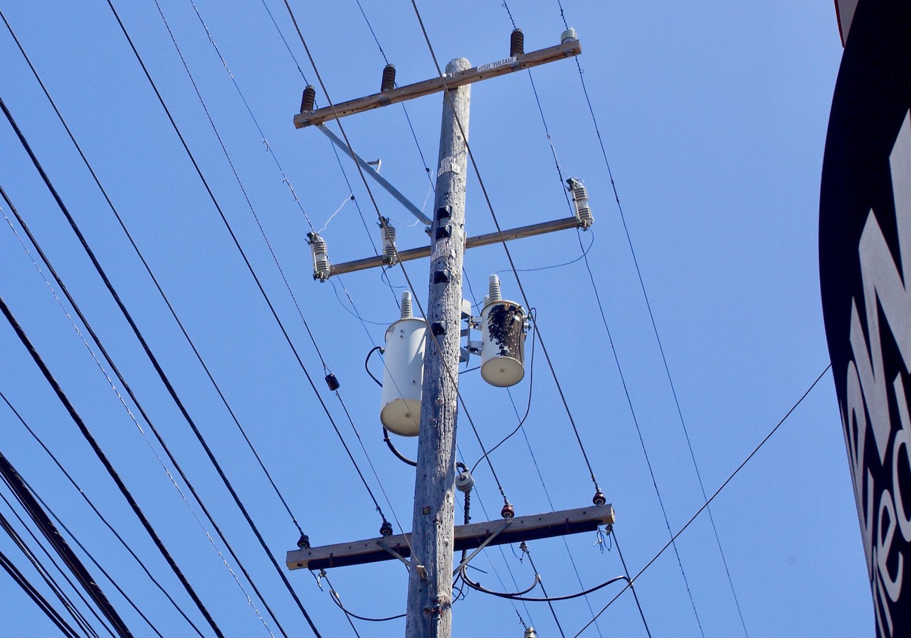 An electricity pole with wires against a blue sky.