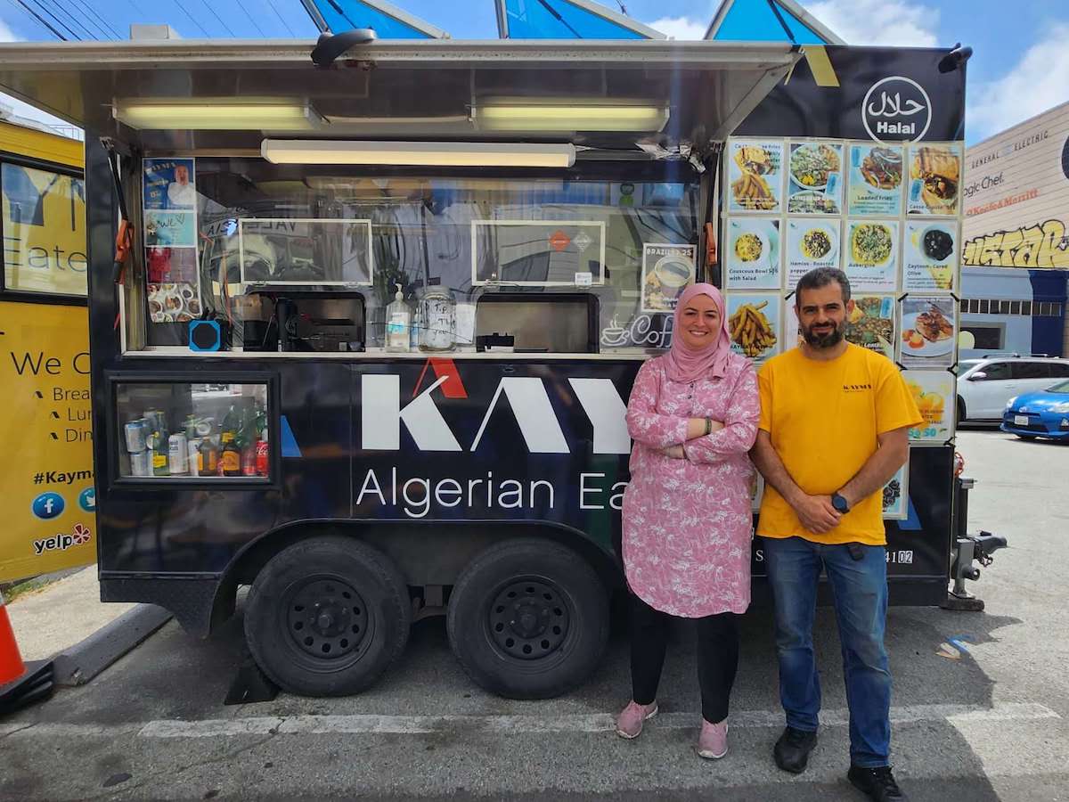 two people standing in front of a food truck