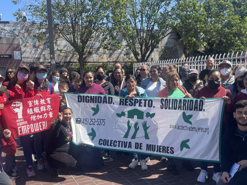 Thirty to forty people gather holding signs saying Chinese Progressive Association and La Colectiva de Mujeres.
