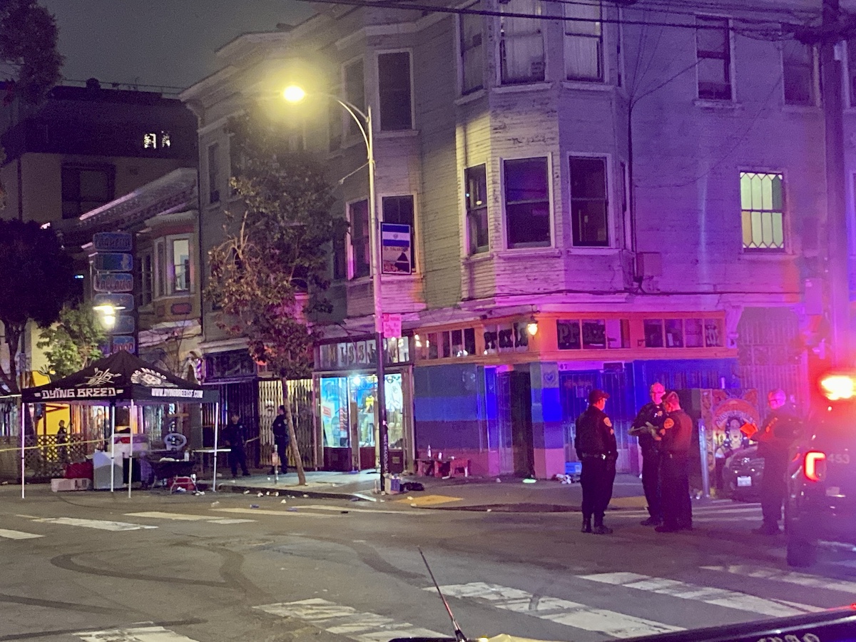 Police near a street corner. Debris and a tent that reads "Dying Breed" are nearby.