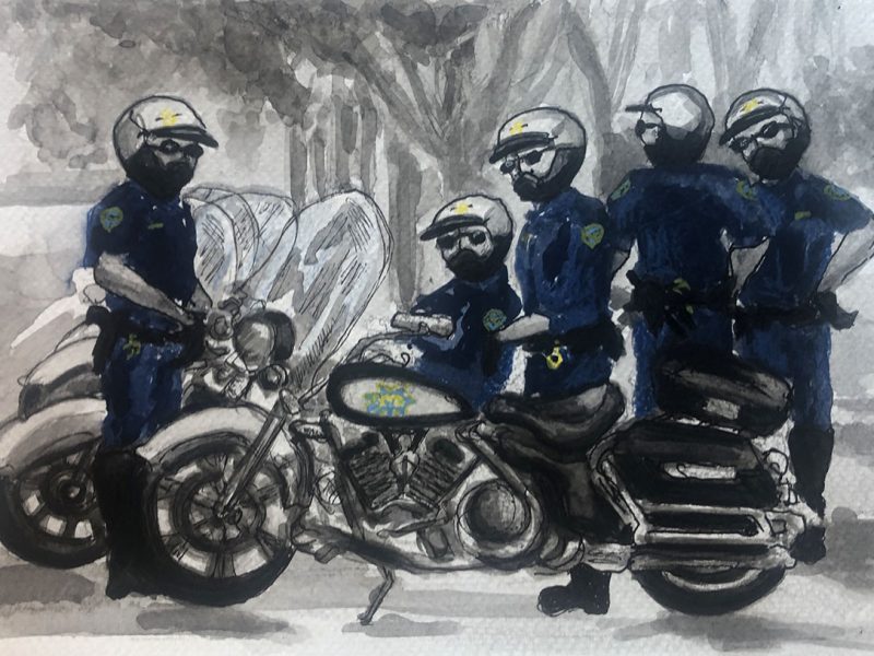 Two officers on motorbikes and three others standing around.