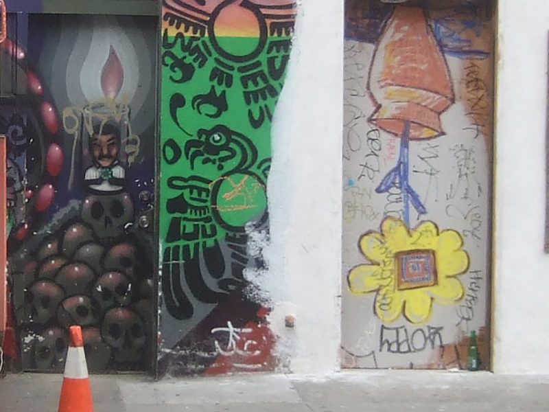 A wall and graffiti including a planted sunflower upside down