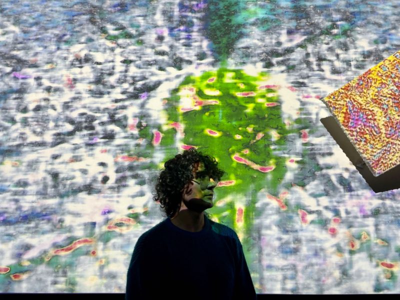 A person standing in front of a colorful background.