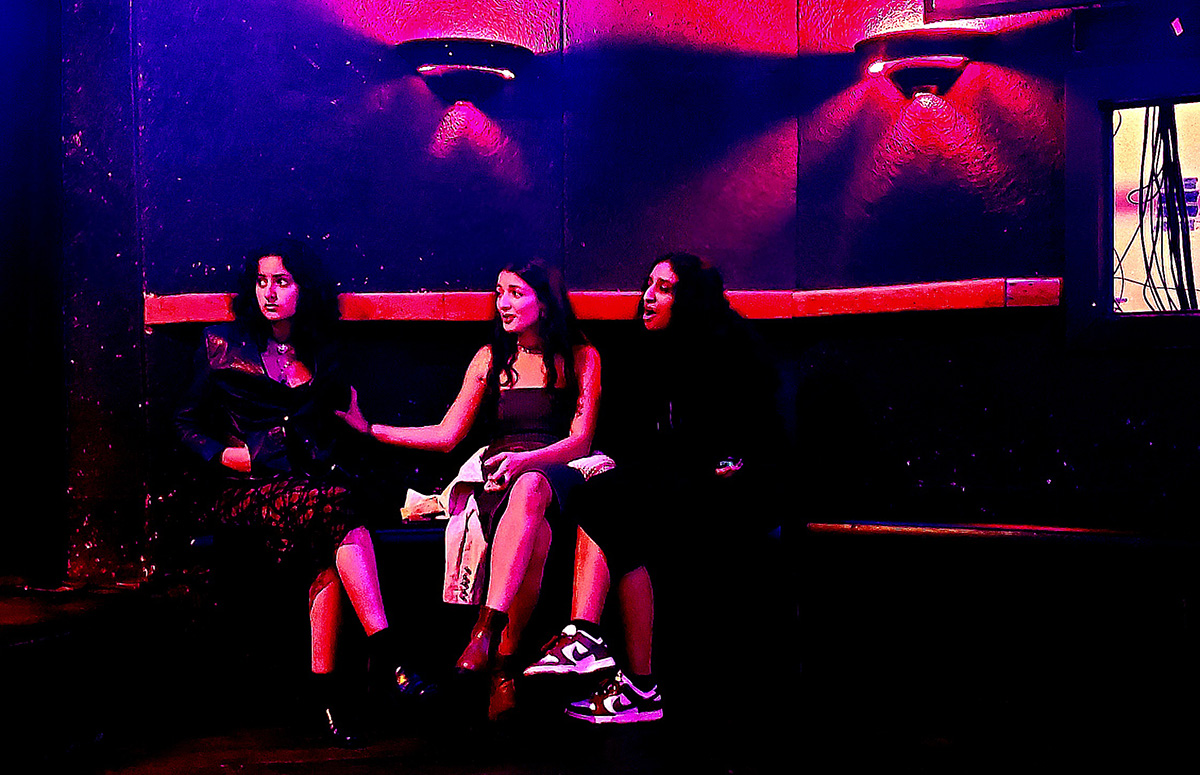 Three women sitting on a bench in a bar