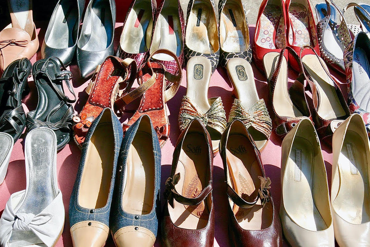 Many pairs of shoes lined up on a sidewalk.